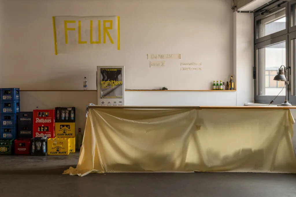 Ausstellungsbesucher im Zeughof Berlin, umgeben von gerahmten Fotografien an industriellen Hallenwänden.