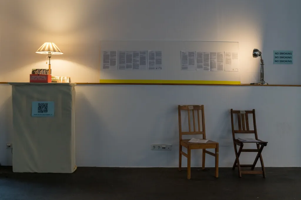 Düstere Atmosphäre in der Ausstellungshalle des Zeughofs mit beleuchteten Fotografien und Besuchern.