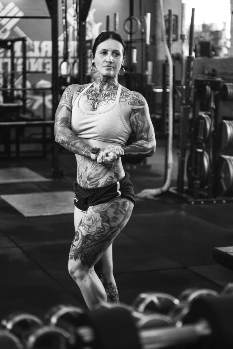 Das Bild ist ein professionelles Schwarzweißporträt, das die Stärke und Ausdauer der Personal Trainerin Caro hervorhebt. Die monochrome Farbgebung verstärkt den Eindruck von Kraft und Fokus.