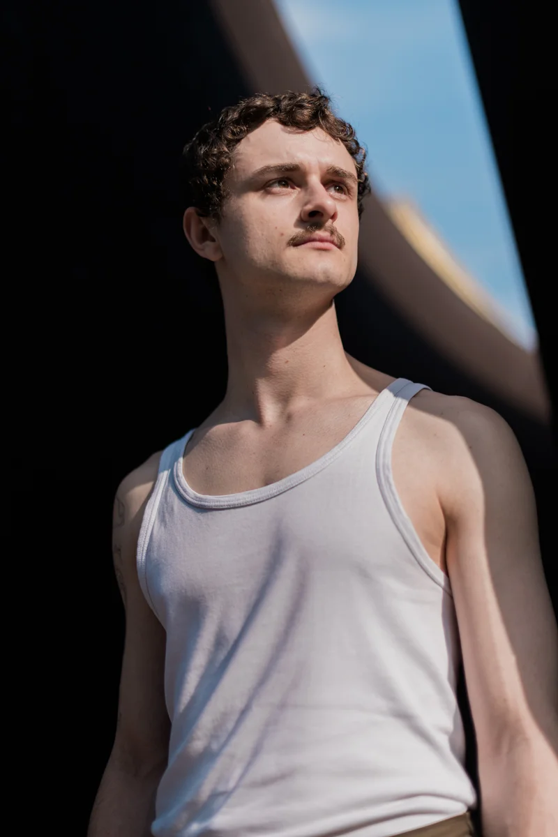 Das Bild zeigt ein Schauspielerportrait von Felix Steinhilber, einem jungen Mann, der nach oben blickt. Die Pose wirkt konzentriert und nachdenklich. Das Licht ist sonnig und betont die Gesichtszüge